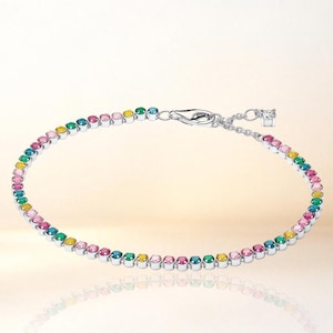 Può includere: Un bracciale tennis color argento caratterizzato da una fila continua di pietre preziose rotonde e multicolori nelle tonalità del rosa, giallo e verde acqua. Il bracciale include una chiusura a moschettone metallica e una catenella di estensione con un piccolo ciondolo quadrato.