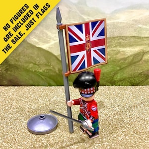 Puede incluir: Una bandera de juguete en miniatura con la Union Jack y un emblema dorado central, unida a un mástil gris con punta de lanza. El texto NO FIGURES ARE INCLUDED IN THE SALE, JUST FLAGS aparece impreso en la esquina. Incluye una base circular gris.