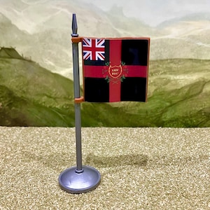 May include: A miniature flag on a silver-coloured pole and circular base. The flag is black with a red cross and a Union Jack in the upper left corner. In the centre of the red cross is a gold shield with the text LXIV REG surrounded by green leaves.
