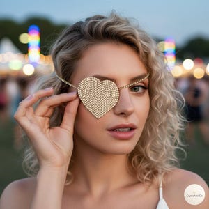 May include: A heart-shaped eye patch covered in small, clear, reflective rhinestones. The patch is attached to a thin, flexible band made of a continuous row of matching rhinestones that wraps around the head to secure the piece in place.