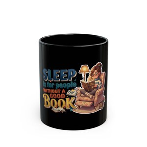 Może przedstawiać: Czarny ceramiczny kubek z grafiką przedstawiającą osobę czytającą w fotelu pod lampą. Tekst głosi: SLEEP is for people WITHOUT A GOOD BOOK. Ilustracja zawiera otwarte książki, mały kubek oraz kota znajdującego się przy podstawie fotela.