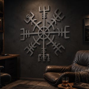 Könnte beinhalten: Ein großes Wandkunstobjekt aus dunkelgrauem Metall, das das Vegvisir-Symbol, auch bekannt als Wikingerkompass, darstellt. Das Design besteht aus einem zentralen Kreis mit acht strahlenförmigen Armen, die jeweils in komplexen geometrischen Mustern enden.