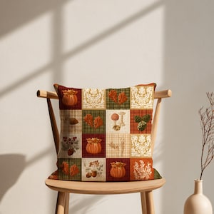 May include: A square throw pillow featuring a patchwork design of twelve distinct panels. The pattern includes illustrations of orange pumpkins, red and brown autumn leaves, pinecones, mushrooms, wheat stalks, and cream-colored floral motifs.
