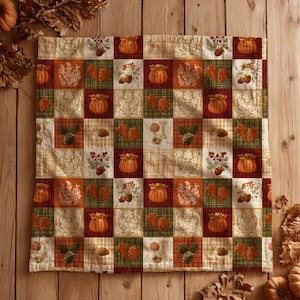 May include: A square fabric pillow cover featuring a patchwork grid design with alternating squares of autumn-themed illustrations including orange pumpkins, brown acorns, green pinecones, and red berries on cream, green, and dark red backgrounds.