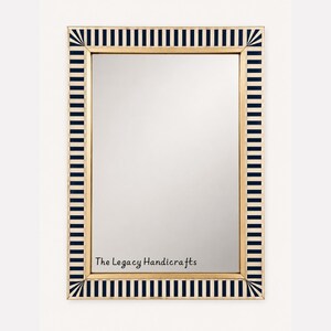 Può includere: Uno specchio da parete rettangolare con una cornice caratterizzata da un motivo ripetitivo di strisce verticali blu navy e color crema. La cornice presenta un bordo interno color oro. Il testo The Legacy Handicrafts è stampato in nero sullo specchio.
