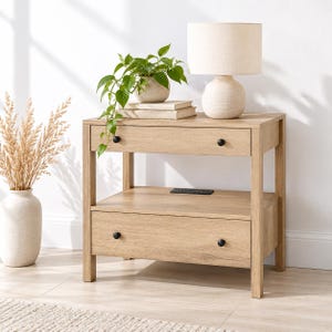 May include: A light oak wood nightstand featuring one top drawer and one bottom drawer, each equipped with two small black circular knobs. The nightstand includes an open middle shelf with a built-in black power outlet strip on the surface.