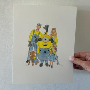 May include: Watercolor illustration of a family with a dog, styled as Minions characters. The figures wear yellow tops and blue overalls. The dog wears a blue vest. The artwork is held by a hand.