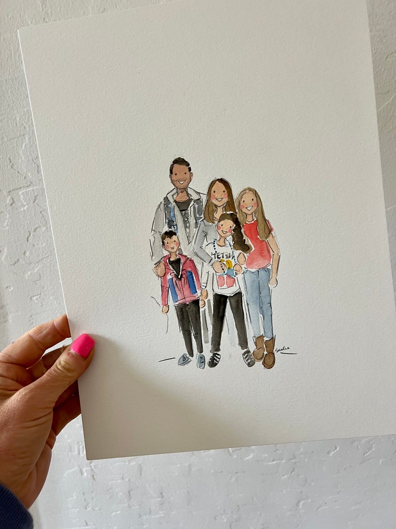 May include: Watercolor portrait of a family of five, featuring two adults and three children. The artwork is on white paper and held by a hand with pink nail polish. The family is dressed in casual attire.