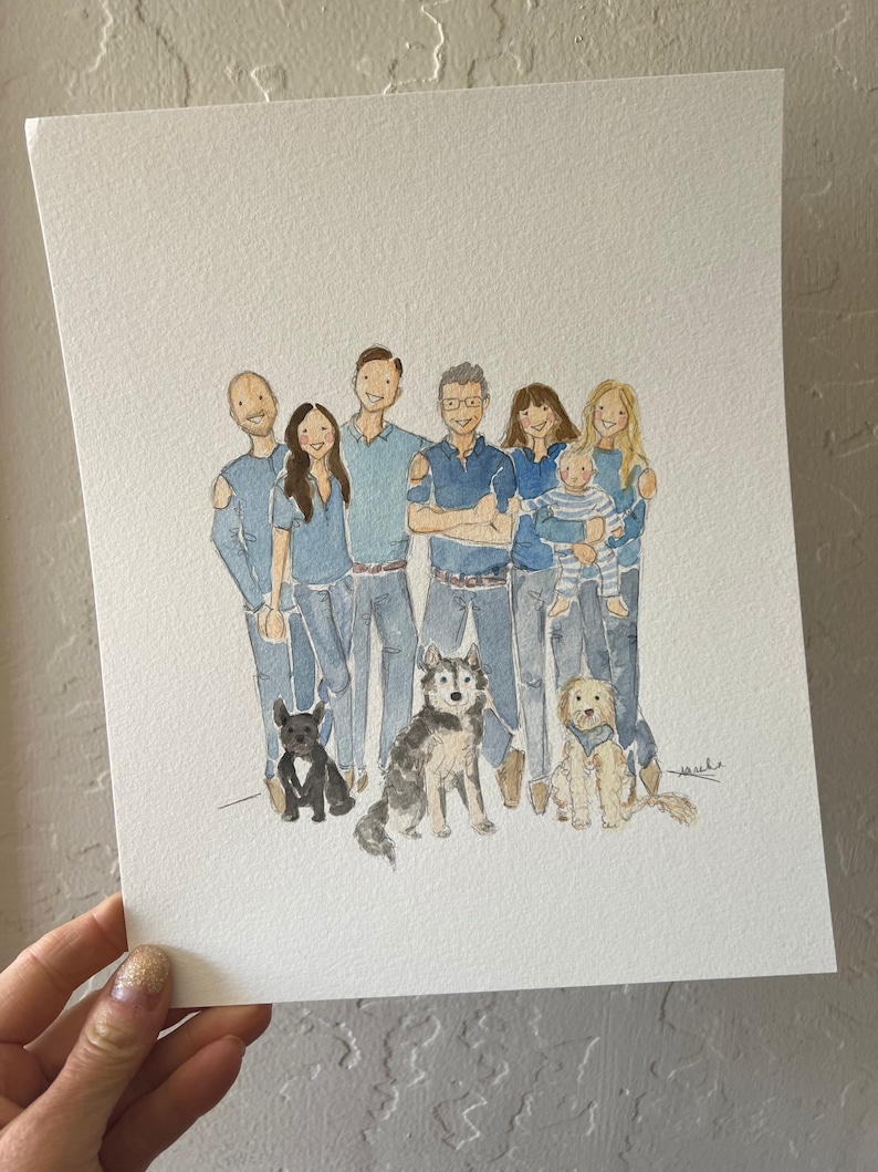 May include: Watercolor portrait of a family and their three dogs. The figures are dressed in shades of blue, with the dogs in front. The artwork is on white paper, held by a hand with glittery nail polish.