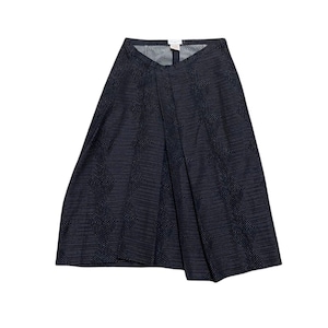 May include: A dark navy blue skirt featuring a repeating geometric diamond pattern in thin white lines. The skirt has a structured waistband, a central vertical pleat detail, and a flared silhouette that falls to a mid-length hemline.