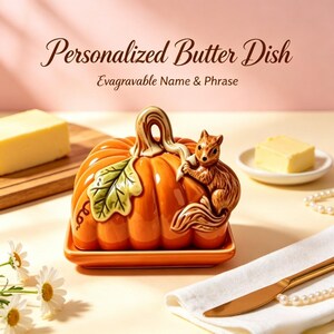 May include: A ceramic butter dish shaped like an orange pumpkin with a brown squirrel perched on the side and a green leaf accent. The lid features a stem handle. Text above reads Personalized Butter Dish and Evagravable Name & Phrase.
