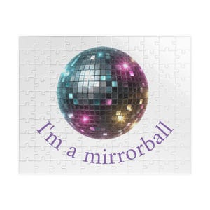 May include: A rectangular jigsaw puzzle featuring a central spherical disco ball composed of numerous small, reflective square mirrors. The ball displays blue, purple, and yellow light reflections. The purple text reads I'm a mirrorball.