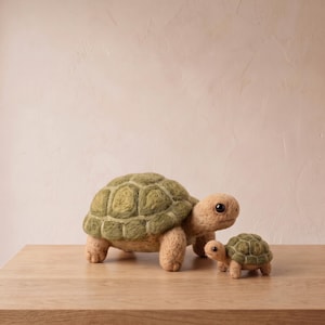 May include: Two needle-felted turtle figurines, one larger and one smaller, both featuring textured tan bodies and olive green shells with defined hexagonal patterns. Each turtle has dark, round eyes and a soft, fuzzy appearance.