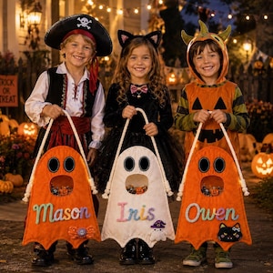 Puede incluir: Tres niños con disfraces de Halloween sostienen bolsas de dulces de fieltro con forma de fantasma. Las bolsas naranjas y blancas tienen ojos y bocas recortados, con los nombres Mason, Iris y Owen bordados y pequeños adornos de fieltro.