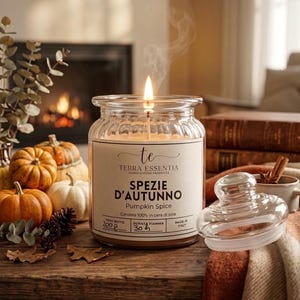 Pode incluir: Uma vela acesa num frasco de vidro canelado com um rótulo que diz Terra Essentia Spezie D'Autunno Pumpkin Spice, 200g, 30h, Made in Italy. A vela tem uma chama visível e fumo, e está ao lado da sua tampa de vidro numa superfície.
