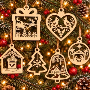 May include: A set of six light-colored wooden ornaments featuring intricate laser-cut designs including a gift box with Santa, a heart with two birds, a mailbox, a pine tree, a bell with a house, and a nativity scene with palm trees.