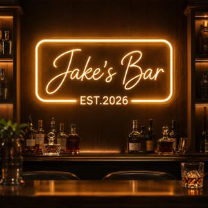 Puede incluir: Un letrero de neón rectangular con esquinas redondeadas que emite un cálido resplandor naranja, mostrando el texto Jake's Bar y EST. 2026 en letra cursiva, montado en una pared de madera oscura sobre una barra llena de botellas de licor.