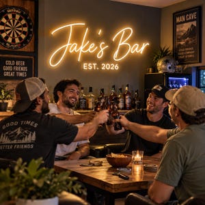Puede incluir: Un letrero de neón amarillo cálido montado en una pared que muestra el texto Jake's Bar EST. 2026 en una fuente cursiva y sans-serif. El letrero ilumina el área circundante, proyectando un brillo suave sobre una barra de madera con botellas.