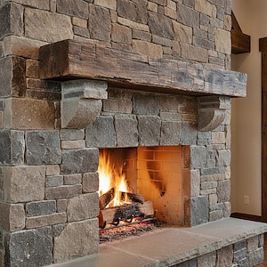 May include: A fireplace constructed from multi-colored rectangular stones in shades of gray and tan. A thick, dark brown wooden beam serves as a mantel, supported by two stone corbels. A fire burns within the hearth, which has a light brick interior.