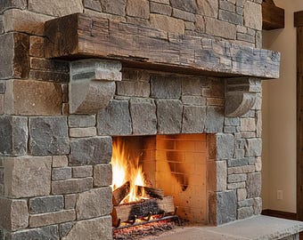 May include: A fireplace constructed from multi-colored rectangular stones in shades of gray and tan. A thick, dark brown wooden beam serves as a mantel, supported by two stone corbels. A fire burns within the hearth, which has a light brick interior.