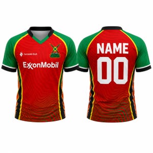 May include: A red, green, and yellow sports jersey featuring the Guyana Amazon Warriors logo, ExxonMobil text, and Lucozade Rush logo on the front. The back displays the word NAME and the number 00 in white block lettering on a red background.