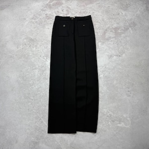 May include: A pair of black high-waisted trousers featuring a wide-leg silhouette, a central button closure at the waistband, and two front patch pockets, each accented with a single matching black button and vertical seam detailing down the legs.