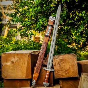 Peut inclure: Une épée en acier à double tranchant avec une poignée gainée de cuir et un pommeau en métal, accompagnée d'un fourreau en bois orné de motifs de nœuds sculptés et de garnitures en métal argenté à la pointe et près de l'embouchure.