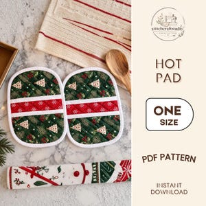 May include: Two oval quilted hot pads featuring a dark green fabric with a pattern of white Christmas trees, red berries, and pine needles, accented by a central horizontal red stripe with white snowflakes, finished with white trim.