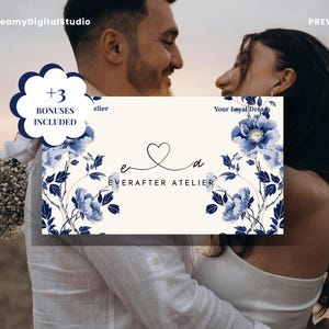 May include: A rectangular business card featuring a cream background with blue floral illustrations on the left and right sides. The center displays a heart icon above the lowercase letters e and a, with the text EVERAFTER ATELIER below.