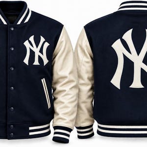 May include: A navy blue and cream varsity jacket featuring a snap-button front, striped ribbed collar, cuffs, and hem. The front left chest and the back display the white New York Yankees NY logo. The sleeves are cream-colored.