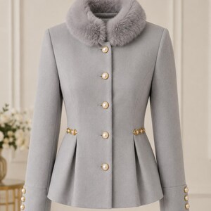 May include: A light gray jacket featuring a plush faux fur collar, long sleeves with three pearl-style buttons at each cuff, and a front closure with five matching pearl-style buttons. The waist is accented with gold-toned decorative trim.