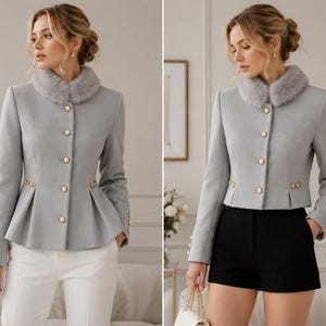 May include: A light gray jacket featuring a faux fur collar, long sleeves, and a peplum hem. The jacket is adorned with a vertical row of round white buttons down the front, with additional buttons on the cuffs and at the waistline.