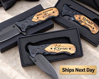 May include: Three folding pocket knives with matte black blades and handles featuring wood grain inlays. Each knife is housed in a black gift box. The knives are engraved with the text Happy Anniversary J&T 2-14-22, BRIAN GROOMSMEN, and Kevin.