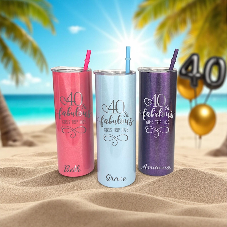 Puede incluir: Tres vasos personalizados con pajitas, en rosa, azul claro y morado, se exhiben en una playa de arena. Cada vaso tiene el texto "40 & Fabulous Girls Trip 2025" y un nombre. El fondo presenta palmeras y el oc&eacute;ano.