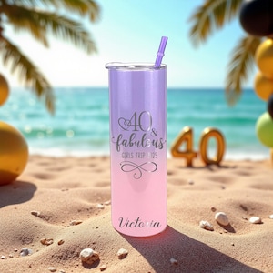 Puede incluir: Un vaso degradado morado y rosa con tapa y pajita plateadas. El vaso tiene el texto "40 & fabulous GIRLS TRIP 2025" y "Victoria" en plata. El vaso est&aacute; en una playa de arena con un fondo de oc&eacute;ano azul.