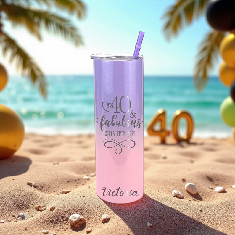Puede incluir: Un vaso degradado morado y rosa con tapa y pajita plateadas. El vaso tiene el texto "40 & fabulous GIRLS TRIP 2025" y "Victoria" en plata. El vaso est&aacute; en una playa de arena con un fondo de oc&eacute;ano azul.