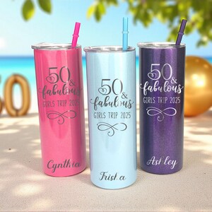 K&ouml;nnte beinhalten: Drei personalisierte Becher mit Strohhalmen in Pink, Hellblau und Lila. Jeder Becher tr&auml;gt den Text "50 & fabulous GIRLS TRIP 2025" und einen Namen. Der Hintergrund zeigt eine Strandszene und einen goldenen Ballon.