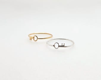 Pode incluir: Dois anéis simples em forma de chave, um dourado e outro prateado. Os anéis são delicados e minimalistas.