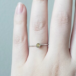 May include: A delicate silver ring with a small, round, light green gemstone.