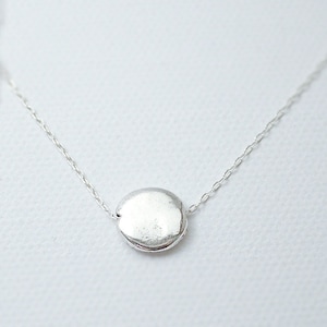 May include: A silver chain necklace with a round silver pendant.