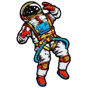 May include: An embroidered patch featuring an astronaut in a white suit with a black helmet visor. The suit includes bright orange, yellow, and blue accents on the harness, gloves, boots, and life support pack, all outlined in a thick black border.