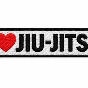 May include: A rectangular embroidered patch with a white background and a thick black border. The text reads I, followed by a red heart symbol, and the word JIU-JITSU in bold black capital letters. The design is centered on the patch.