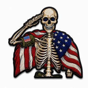 May include: An embroidered patch featuring a skeleton saluting while draped in an American flag. The skeleton has a beige bone color, and the flag displays red and white stripes with a blue field containing white stars. A small flag patch is on the sleeve.