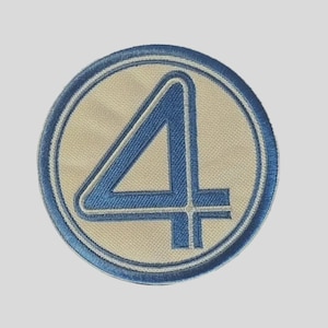 May include: A circular embroidered patch featuring a large blue number four centered on a light beige background. The design is enclosed within a thick blue circular border, with a thin white inner ring separating the center from the outer edge.
