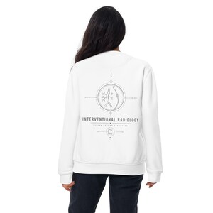 May include: A white long-sleeve sweatshirt featuring a gray graphic on the back. The design includes a circular medical illustration of vascular structures, the text "INTERVENTIONAL RADIOLOGY" and "VISION BEYOND STRUCTURE," and a small icon.
