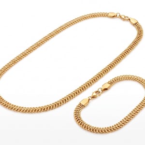 Puede incluir: Un collar de cadena y una pulsera a juego en metal de tono dorado, ambos con un patrón denso de eslabones trenzados. Cada pieza cuenta con un cierre de mosquetón de metal pulido y terminales seguros, logrando un aspecto texturizado uniforme.