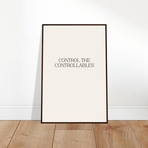 Könnte beinhalten: Ein rechteckiges Wandbild mit cremefarbenem Hintergrund in einem dünnen, dunkelbraunen Rahmen. Der Text "CONTROL THE CONTROLLABLES" ist mittig in einer dunklen Serifenschrift in Großbuchstaben gedruckt und bildet ein klares visuelles Element.