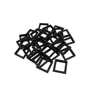 May include: A collection of numerous small, black, square-shaped frames arranged in a loose, overlapping pile. Each frame features a simple, flat border design with a hollow centre, creating a uniform appearance across the entire group of items.