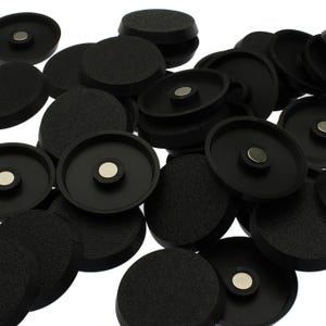 May include: A collection of circular black plastic components, each featuring a textured outer surface and a smooth interior rim. A small, circular silver-coloured metal magnet is embedded in the centre of each piece, creating a uniform set.