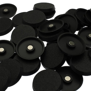 May include: A collection of circular black plastic components, each featuring a textured outer surface and a smooth interior rim. A small, circular silver-coloured metal magnet is embedded in the centre of each piece, creating a uniform set.